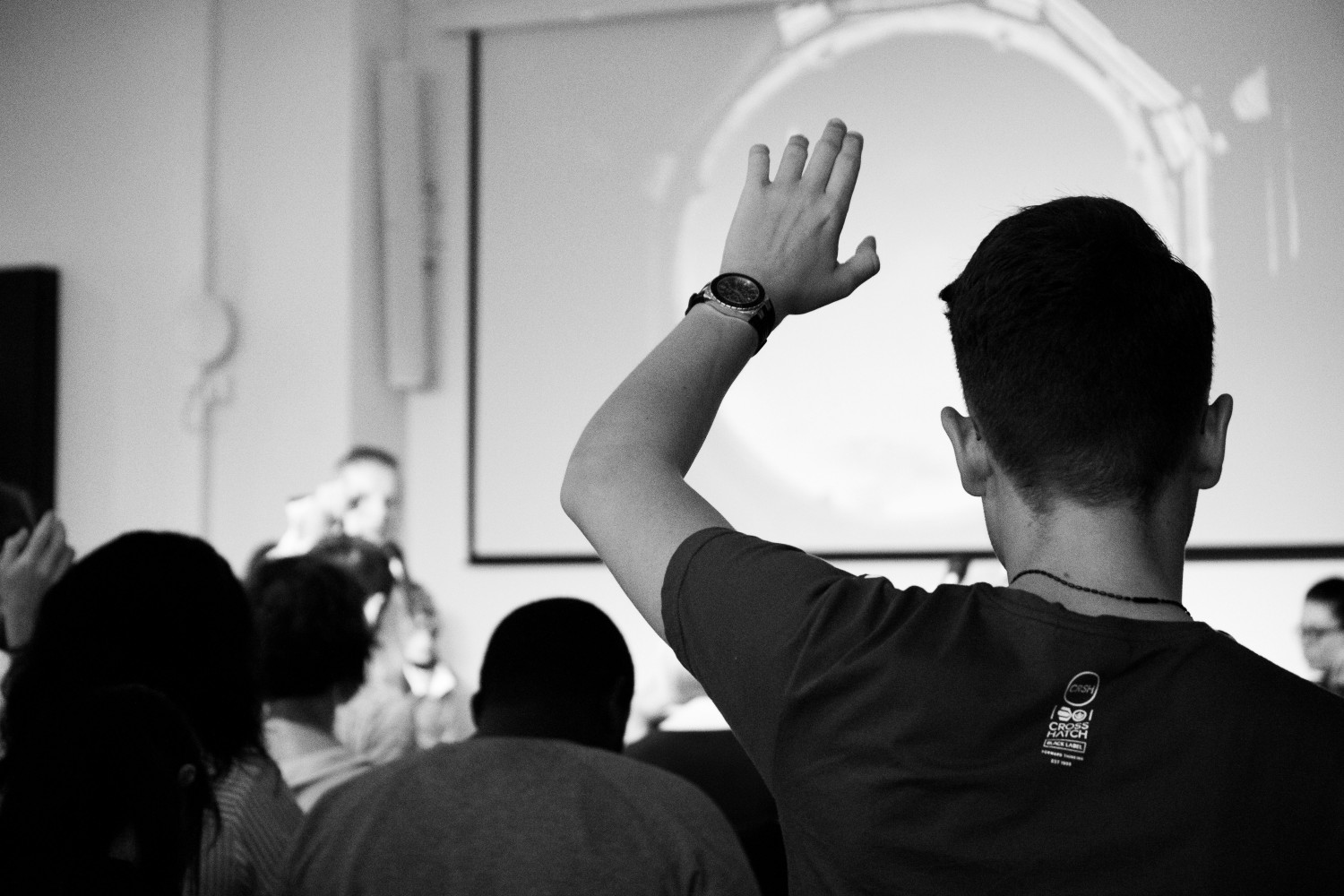 Young man with hand up in classroom