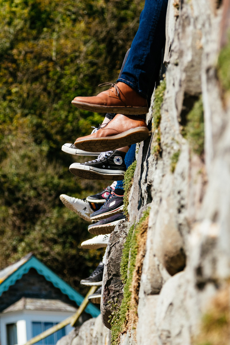 View of feet and legs hanging over a wall